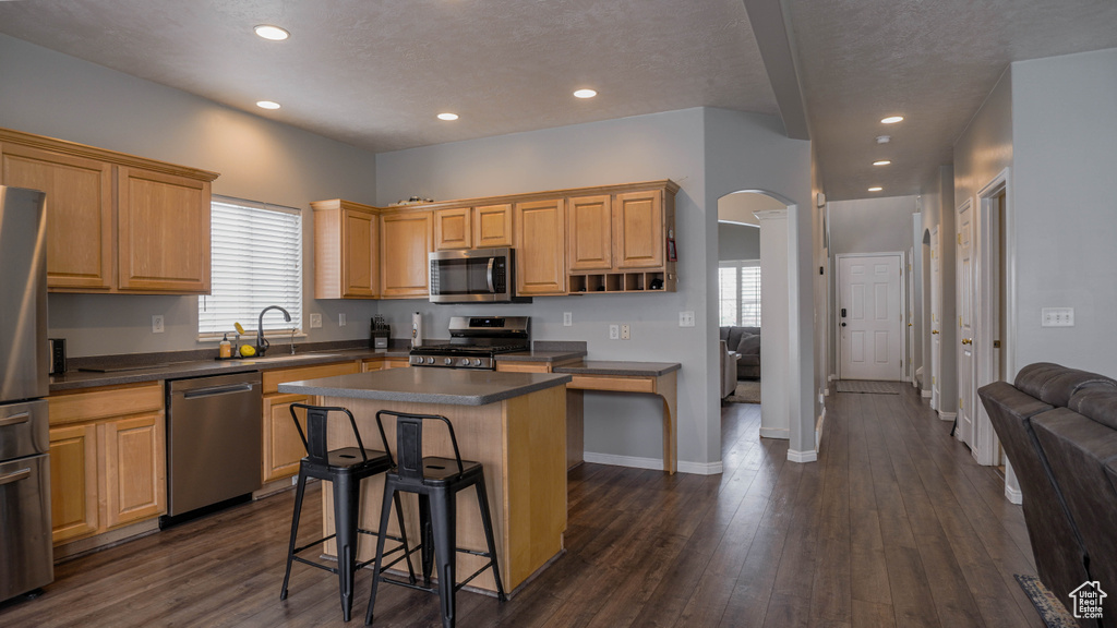 Kitchen featuring a kitchen island, stainless steel appliances, dark hardwood / wood-style floors, and a wealth of natural light