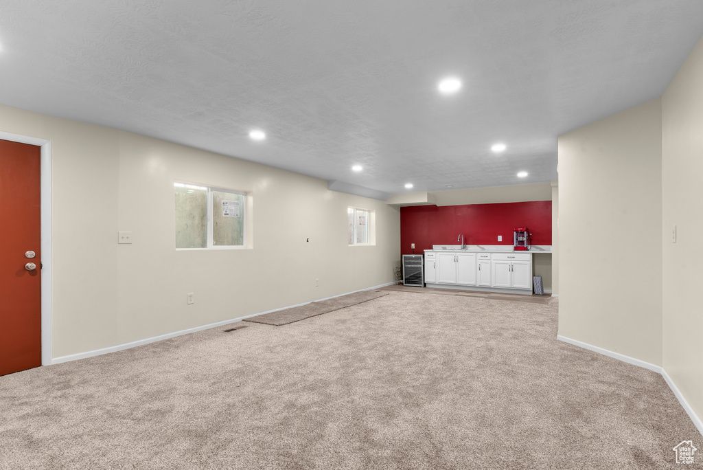 Unfurnished living room with light carpet and sink