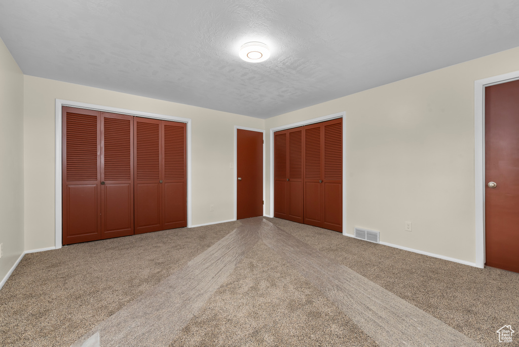 Unfurnished bedroom with carpet floors and multiple closets