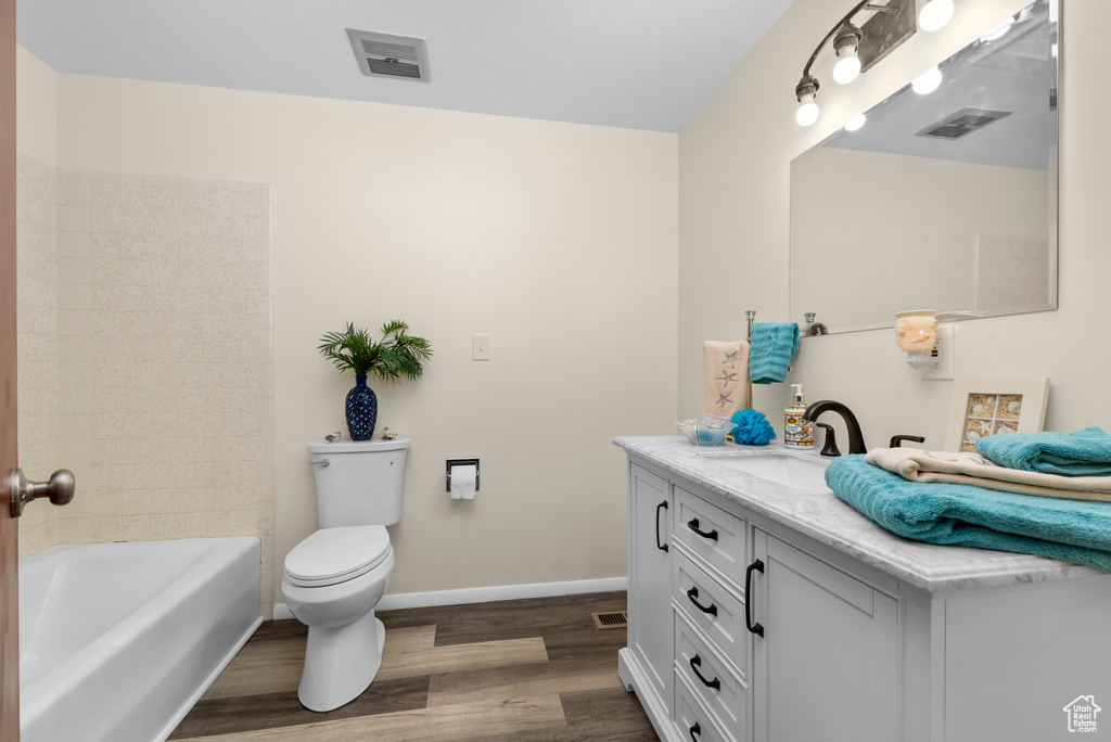 Bathroom with toilet, vanity with extensive cabinet space, and hardwood / wood-style flooring