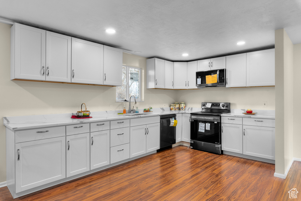 Kitchen featuring dark wood-type flooring, white cabinets, electric range oven, dishwasher, and sink