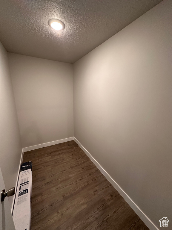 Unfurnished room featuring a textured ceiling and dark hardwood / wood-style flooring