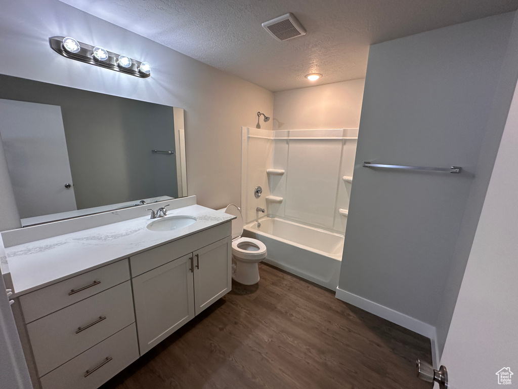 Full bathroom featuring shower / bathing tub combination, a textured ceiling, toilet, oversized vanity, and hardwood / wood-style flooring