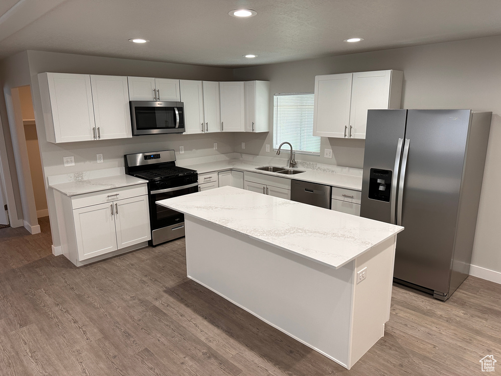 Kitchen with wood-type flooring, appliances with stainless steel finishes, and white cabinetry
