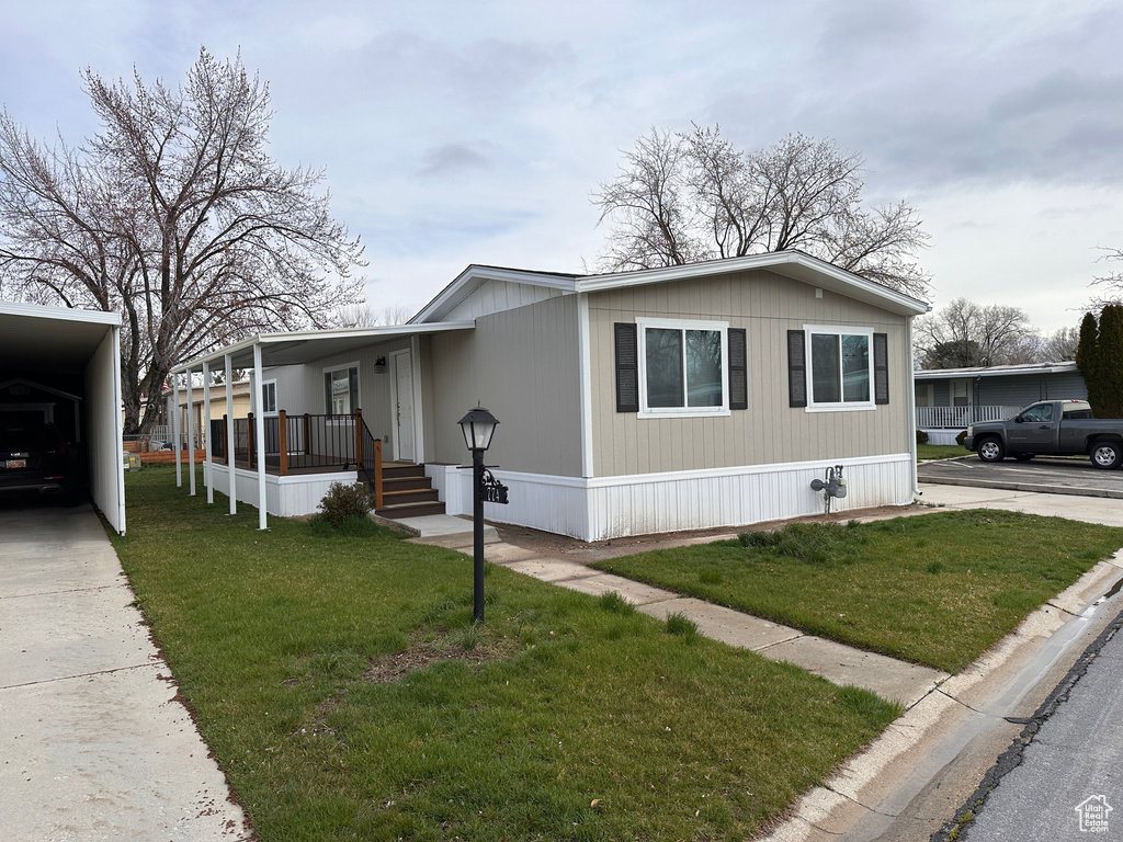 Manufactured / mobile home with a porch, a carport, and a front yard