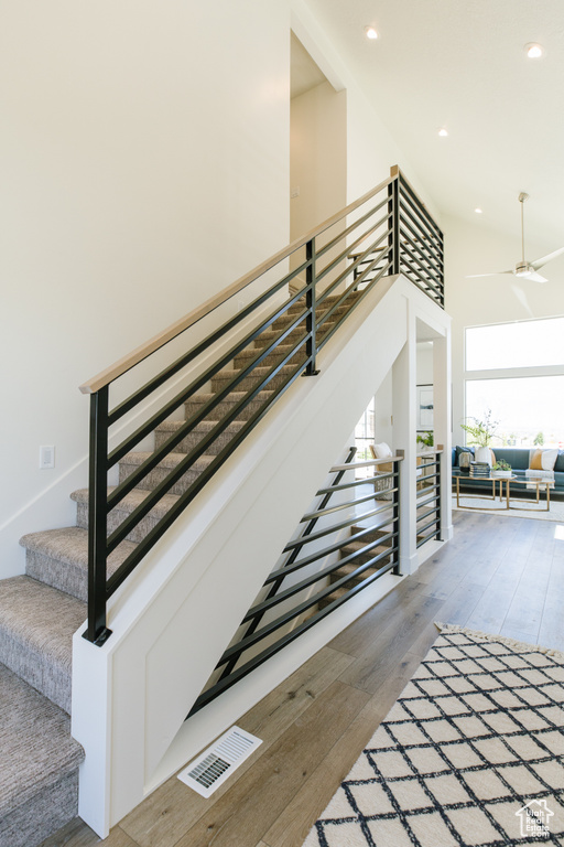 Stairway featuring light hardwood / wood-style flooring, ceiling fan, and a towering ceiling
