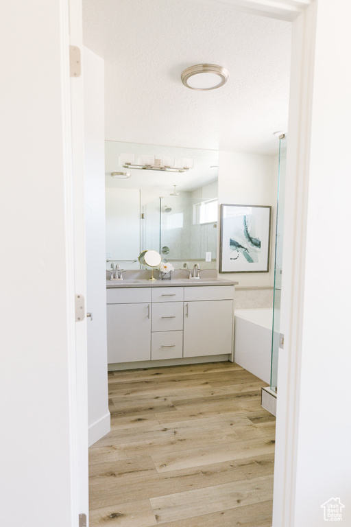 Bathroom featuring double vanity, a textured ceiling, and hardwood / wood-style floors