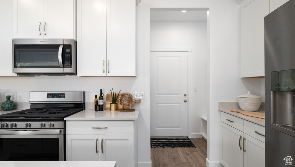 Kitchen with white cabinets, appliances with stainless steel finishes, and wood-type flooring