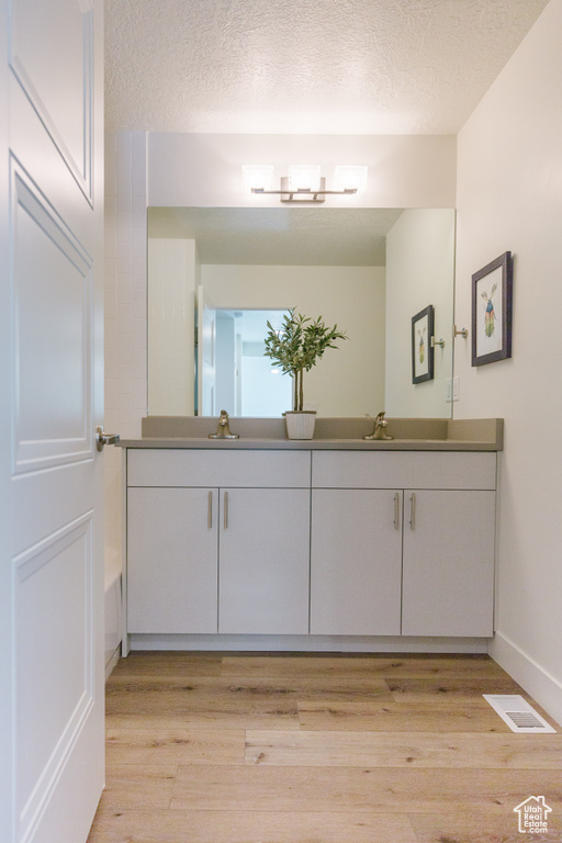 Bathroom featuring hardwood / wood-style floors, dual vanity, and a textured ceiling