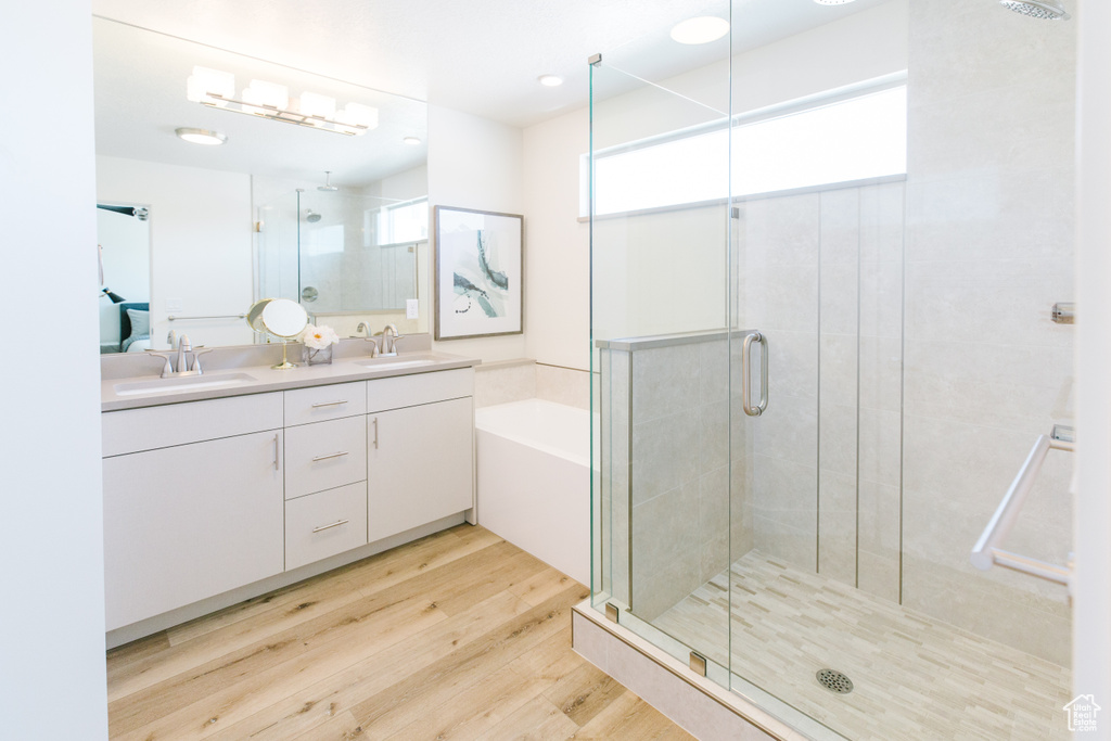 Bathroom featuring double sink, oversized vanity, hardwood / wood-style flooring, and separate shower and tub