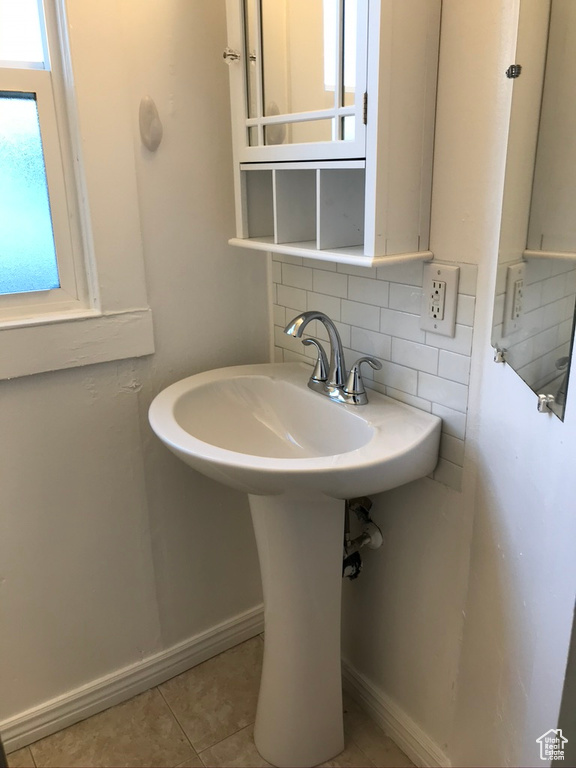 Bathroom featuring tile floors, sink, and tasteful backsplash