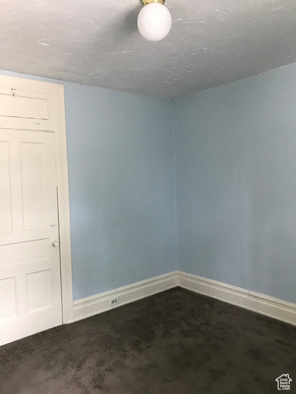 Spare room featuring dark colored carpet