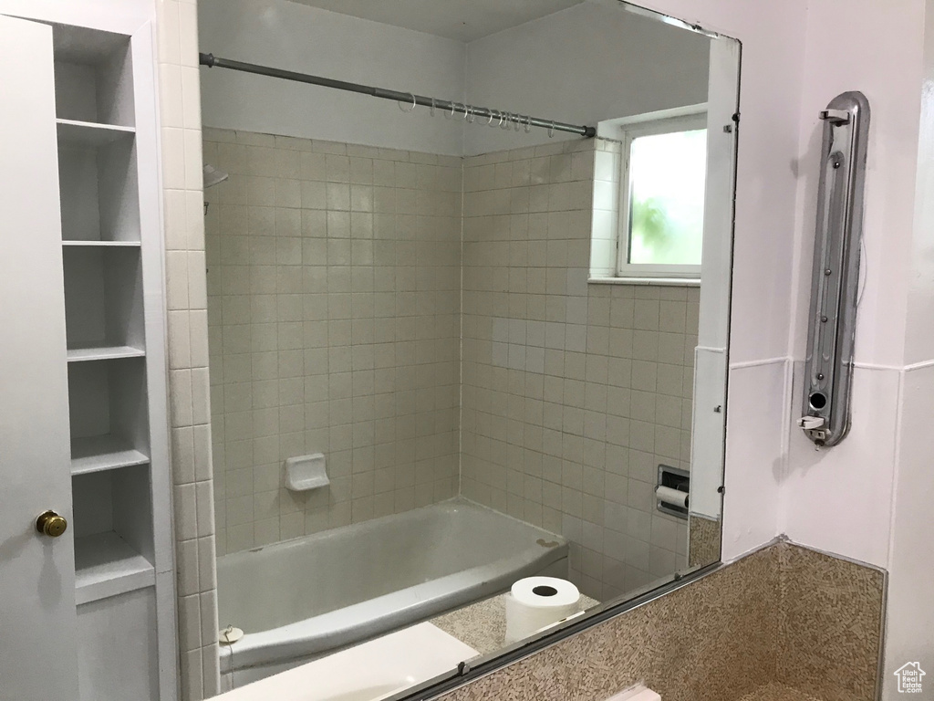 Bathroom with tiled shower / bath and built in shelves