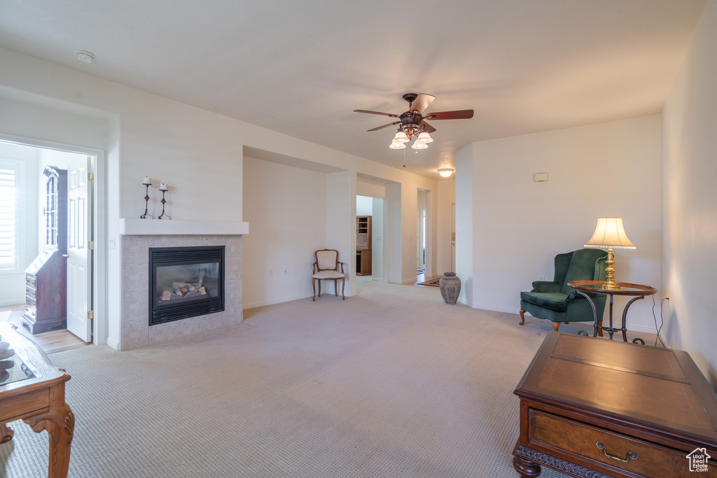 Living room with light carpet, ceiling fan, and a tile fireplace