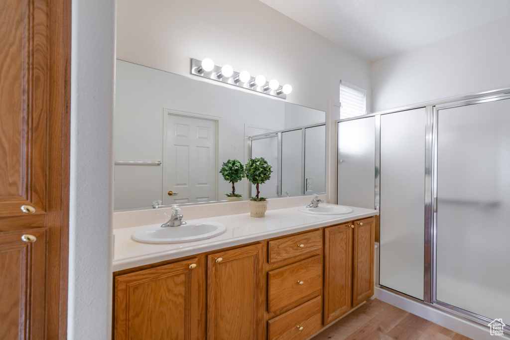 Bathroom with walk in shower, dual sinks, vanity with extensive cabinet space, and hardwood / wood-style flooring