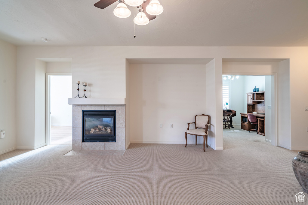 Carpeted living room featuring ceiling fan and a tile fireplace