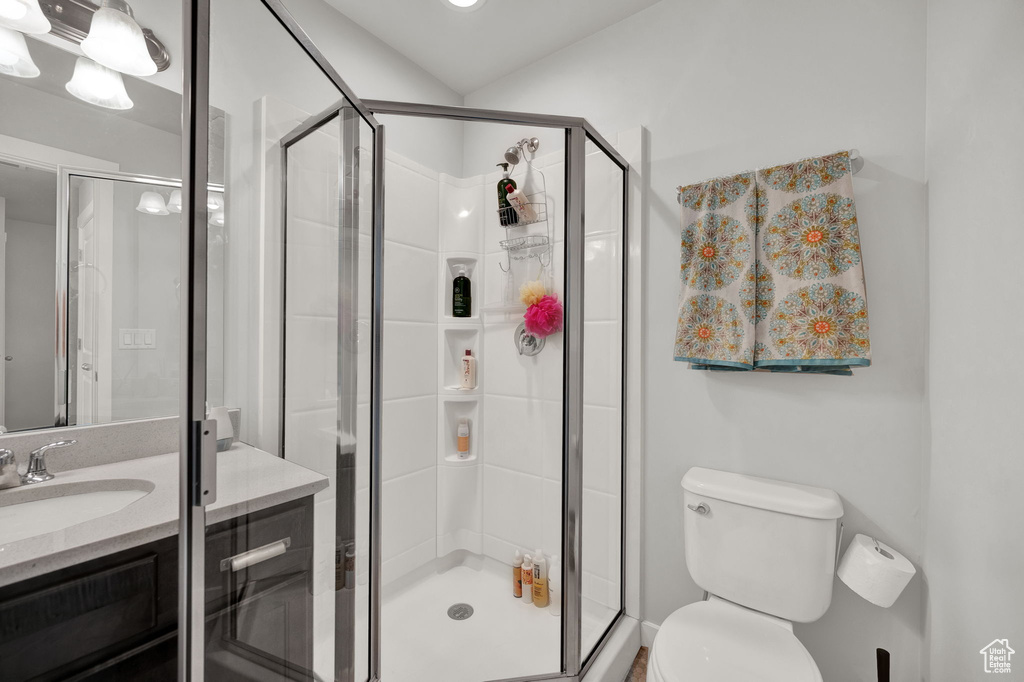 Bathroom featuring a shower with door, toilet, and vanity
