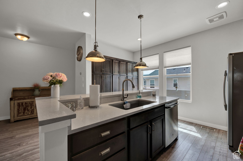Kitchen with pendant lighting, a center island with sink, appliances with stainless steel finishes, dark hardwood / wood-style floors, and sink
