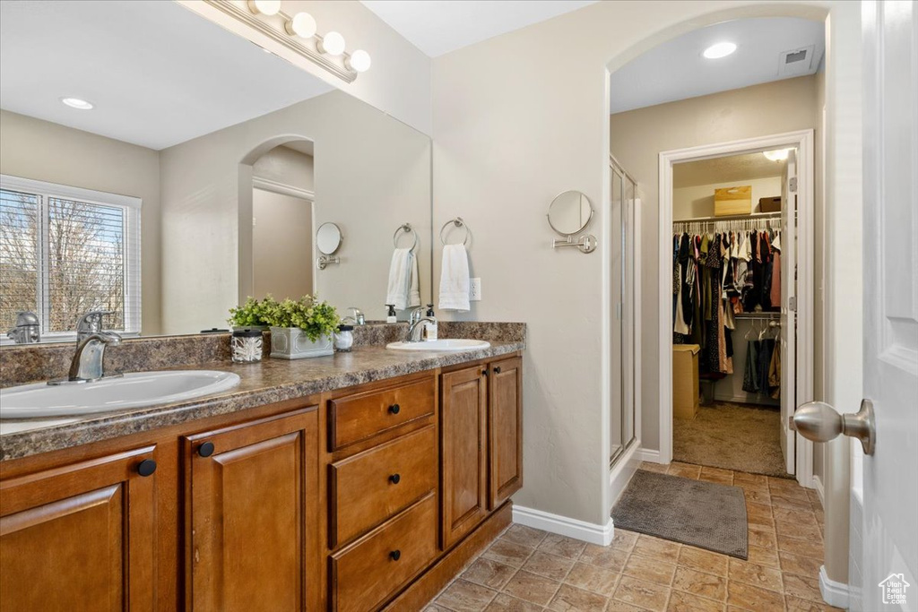 Bathroom featuring oversized vanity, an enclosed shower, tile floors, and double sink