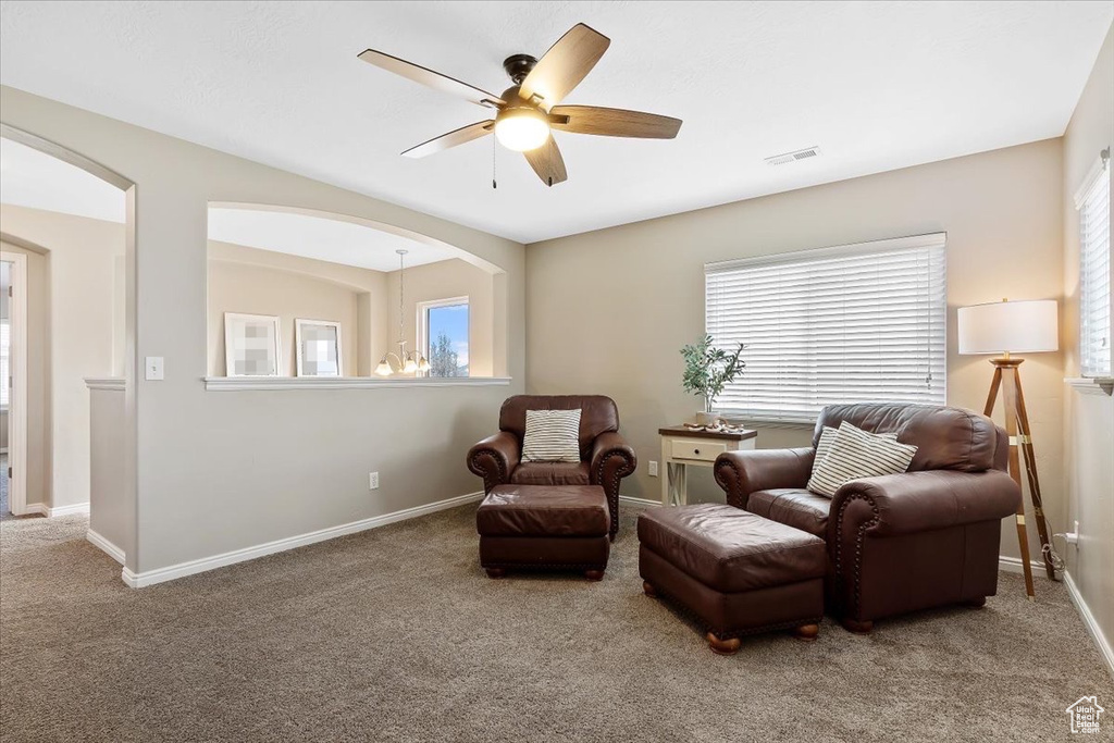 Living area featuring light carpet and ceiling fan with notable chandelier