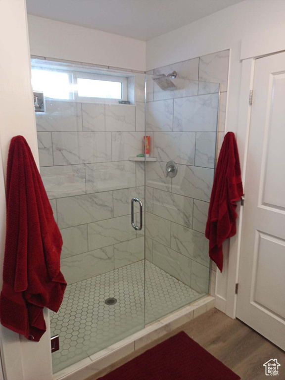 Bathroom with a shower with shower door and hardwood / wood-style flooring
