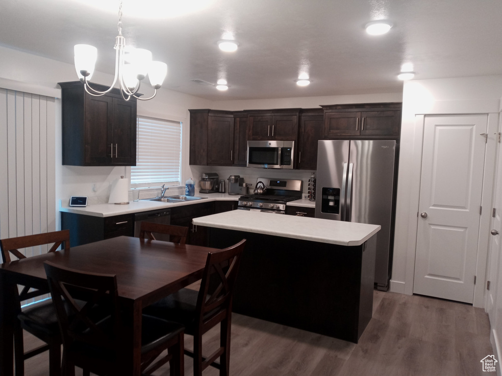 Kitchen featuring decorative light fixtures, light hardwood / wood-style flooring, appliances with stainless steel finishes, dark brown cabinetry, and an inviting chandelier