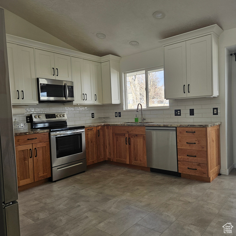 Kitchen with light stone countertops, backsplash, light tile flooring, sink, and stainless steel appliances