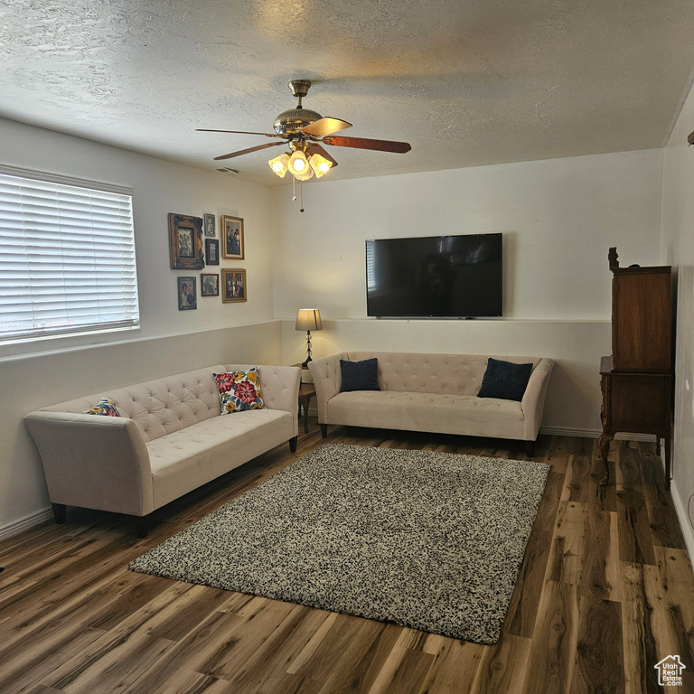Living room with dark hardwood / wood-style floors, a textured ceiling, and ceiling fan