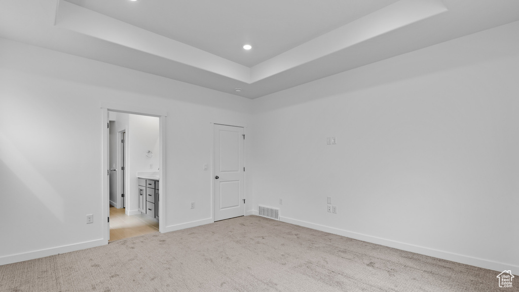 Empty room featuring light colored carpet and a tray ceiling