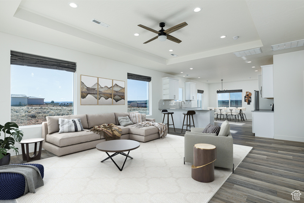 Living room with a healthy amount of sunlight, a raised ceiling, and ceiling fan