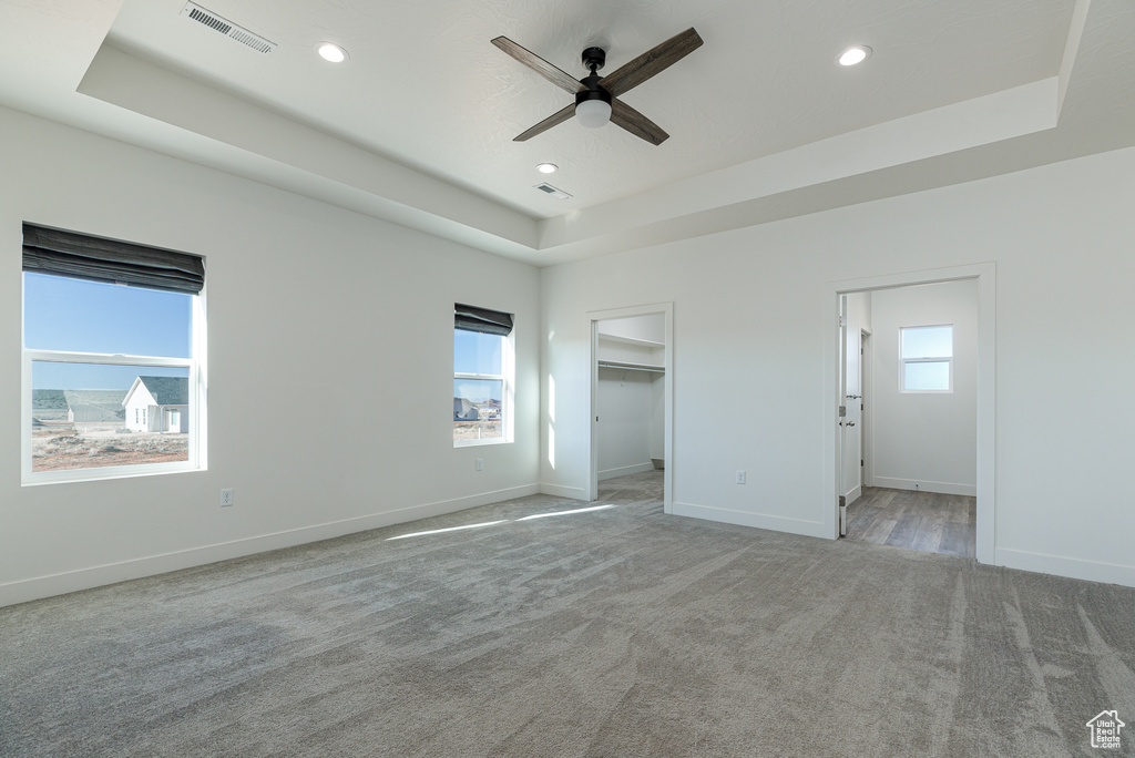 Unfurnished room featuring plenty of natural light, a tray ceiling, and ceiling fan