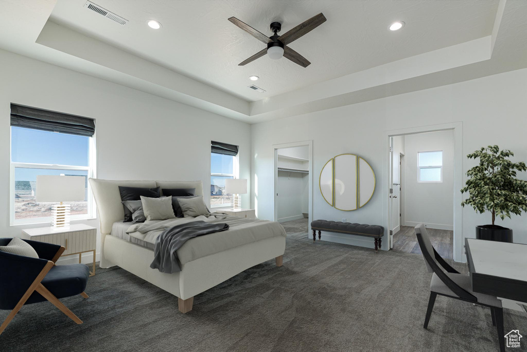 Bedroom with a raised ceiling, ceiling fan, and multiple windows