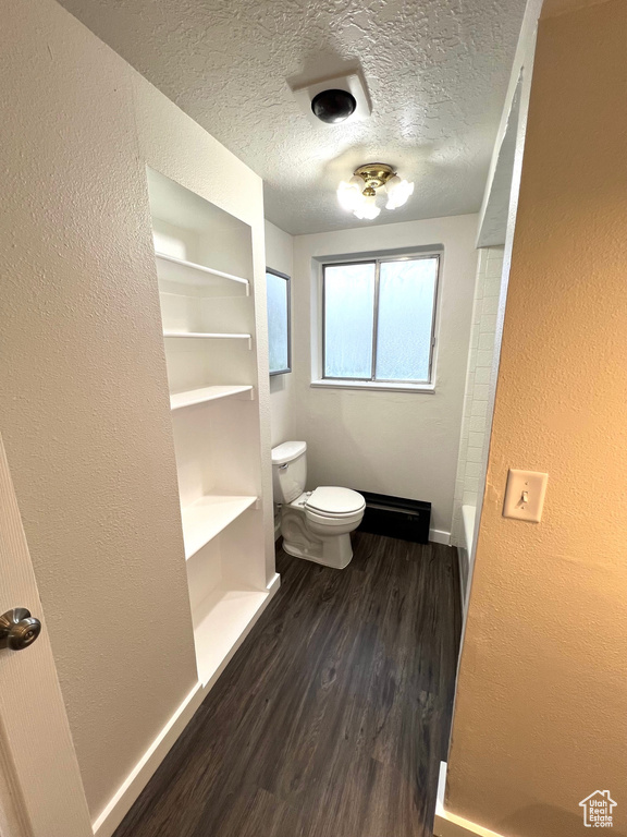 Bathroom with a textured ceiling, toilet, hardwood / wood-style flooring, and built in shelves