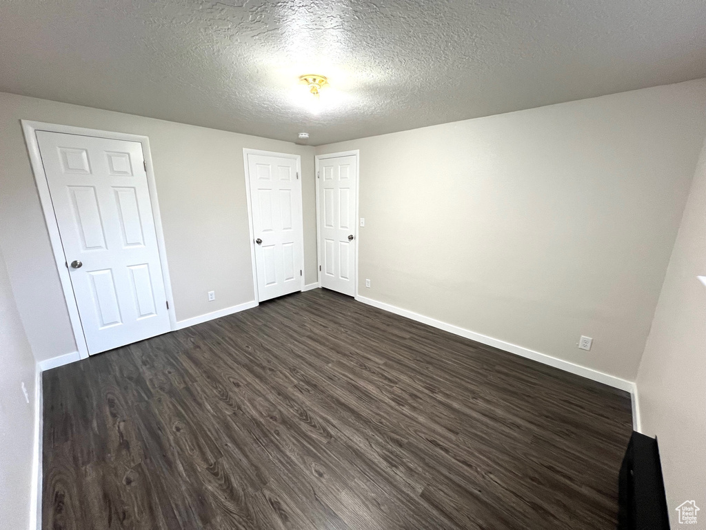 Unfurnished bedroom with dark hardwood / wood-style flooring and a textured ceiling