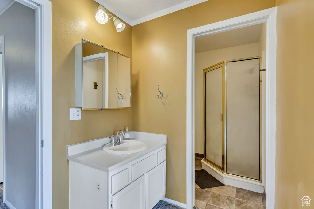 Bathroom with tile flooring, a shower with shower door, and vanity with extensive cabinet space