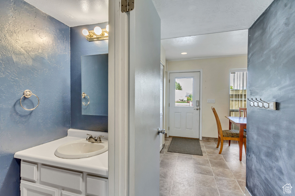 Bathroom featuring vanity with extensive cabinet space, tile floors, and a chandelier