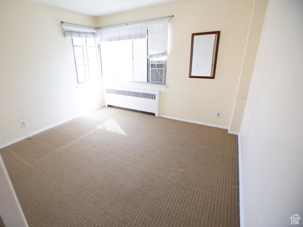 Unfurnished room with dark carpet and radiator heating unit