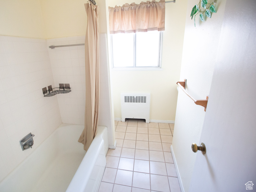 Bathroom featuring radiator, shower / bathtub combination with curtain, and tile flooring