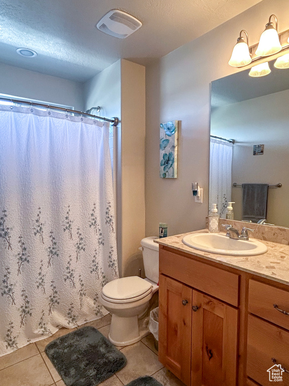 Bathroom featuring toilet, tile flooring, a textured ceiling, and oversized vanity