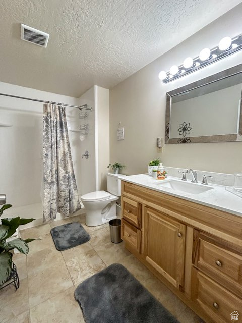 Bathroom featuring toilet, tile flooring, a textured ceiling, and vanity