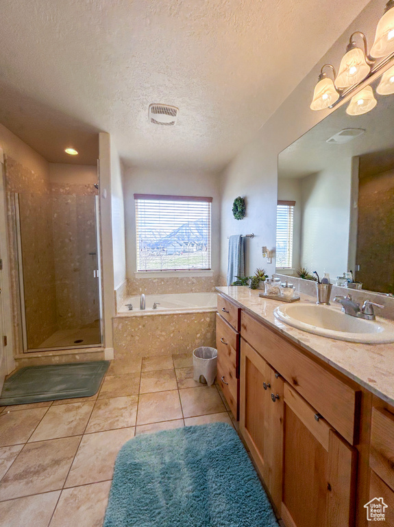 Bathroom with a textured ceiling, vanity, tile floors, and independent shower and bath