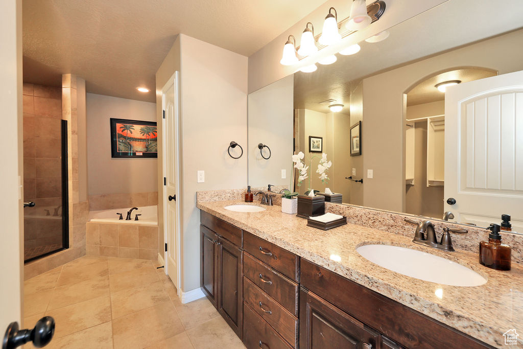 Bathroom featuring double sink vanity, tile floors, and separate shower and tub