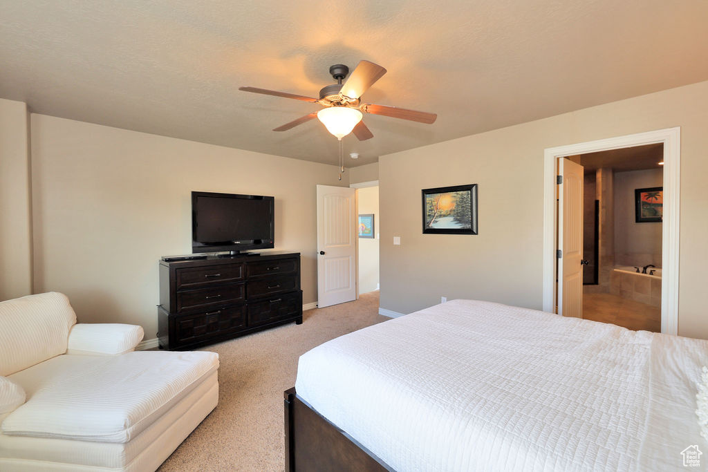 Bedroom with light colored carpet, connected bathroom, and ceiling fan