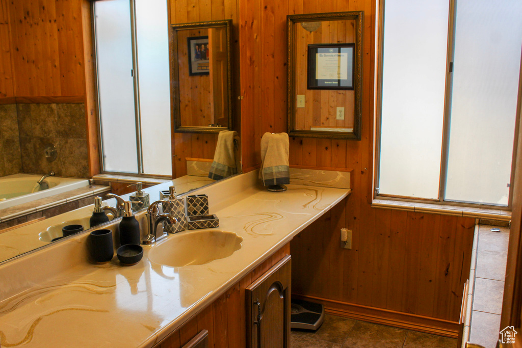 Bathroom featuring a tub, wooden walls, vanity, and tile flooring