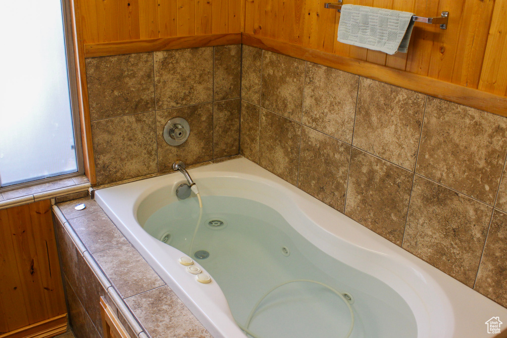 Bathroom with tiled tub and wooden walls