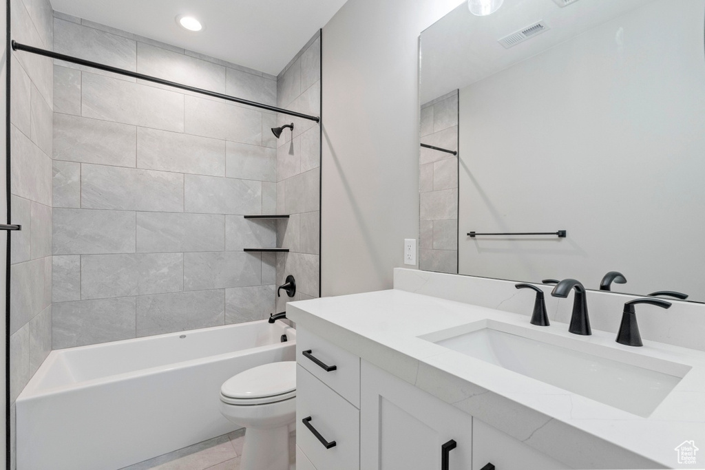 Full bathroom featuring vanity, toilet, tile floors, and tiled shower / bath combo