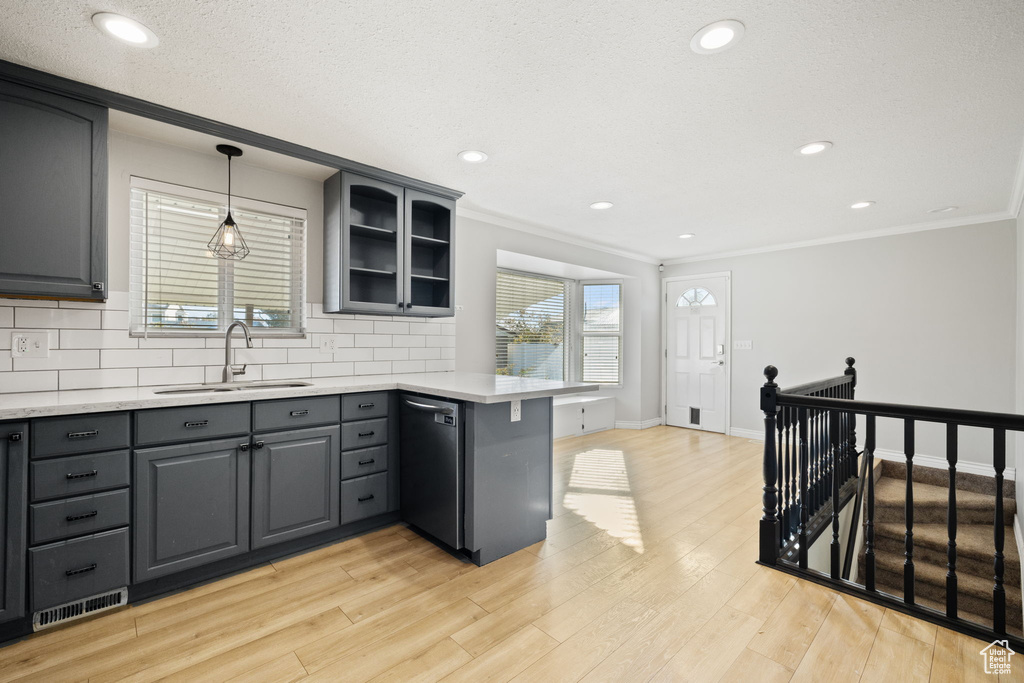 Kitchen with gray cabinets, light hardwood / wood-style flooring, backsplash, hanging light fixtures, and dishwasher