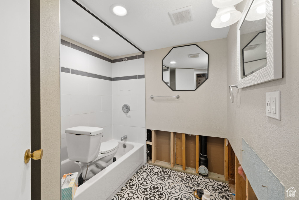 Bathroom with tile flooring, toilet, and tiled shower / bath