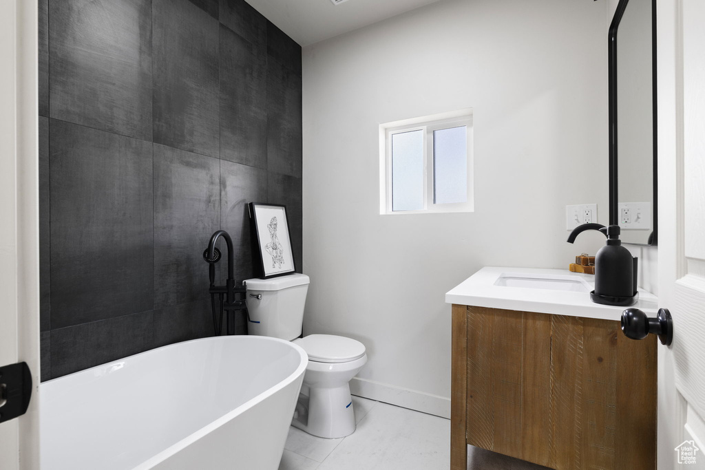 Bathroom featuring toilet, tile floors, vanity, and a tub