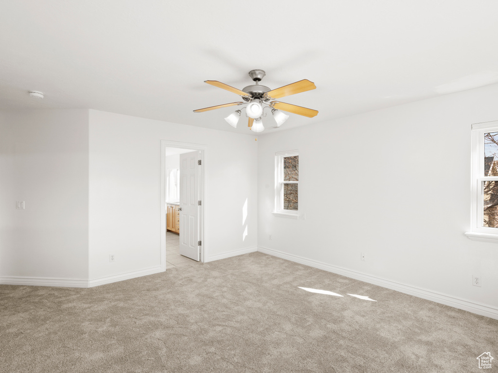 Carpeted spare room with plenty of natural light and ceiling fan